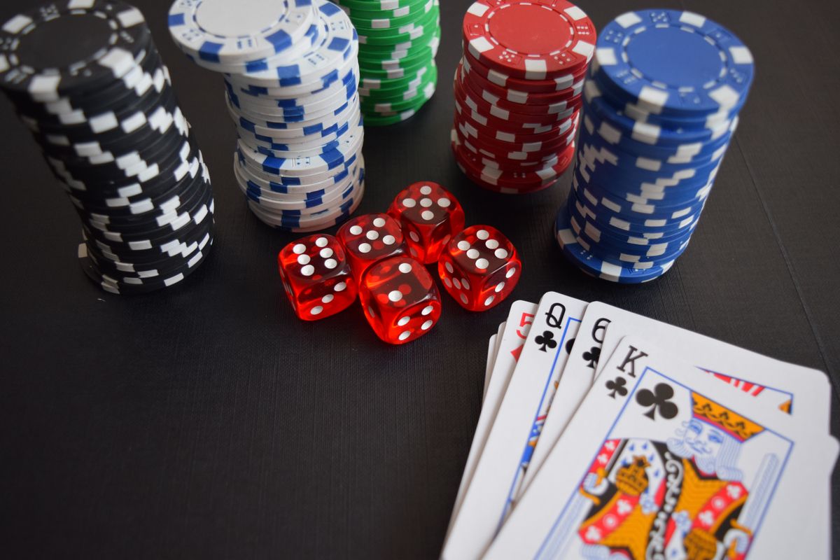 Chip kasino, dadu, dan kartu remi tersusun di atas meja
